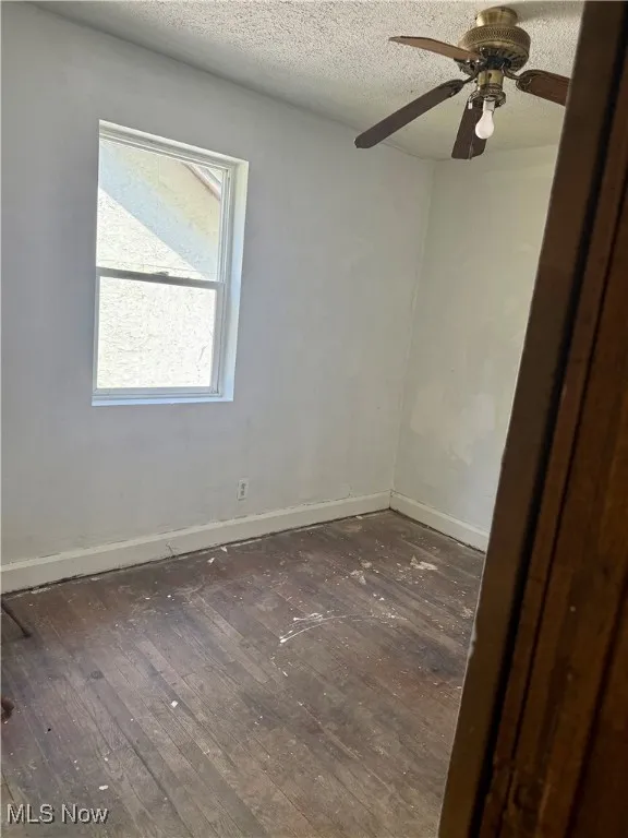 Unfurnished room with wood-type flooring, a textured ceiling, and ceiling fan