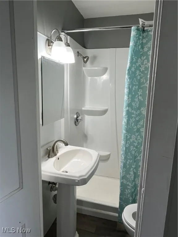 Full bathroom featuring curtained shower and wood finished floors