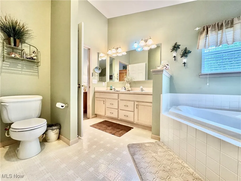 Bathroom with double vanity, a garden tub, and tile patterned floors