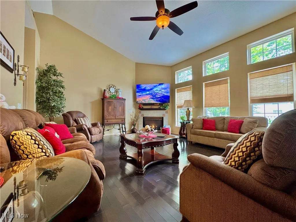 Great room with a ceiling fan, dark flooring, a gas fireplace, and high vaulted ceiling