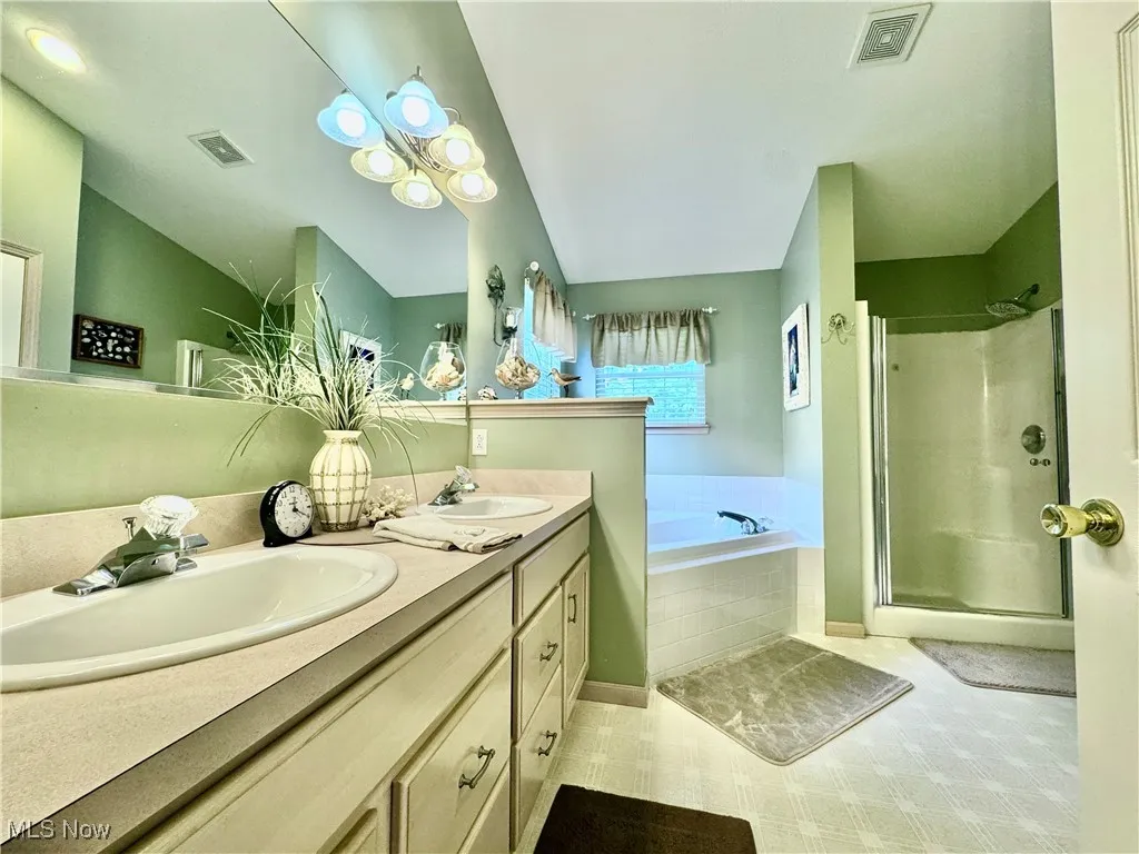 Full bathroom featuring double vanity, a bath, and a shower stall