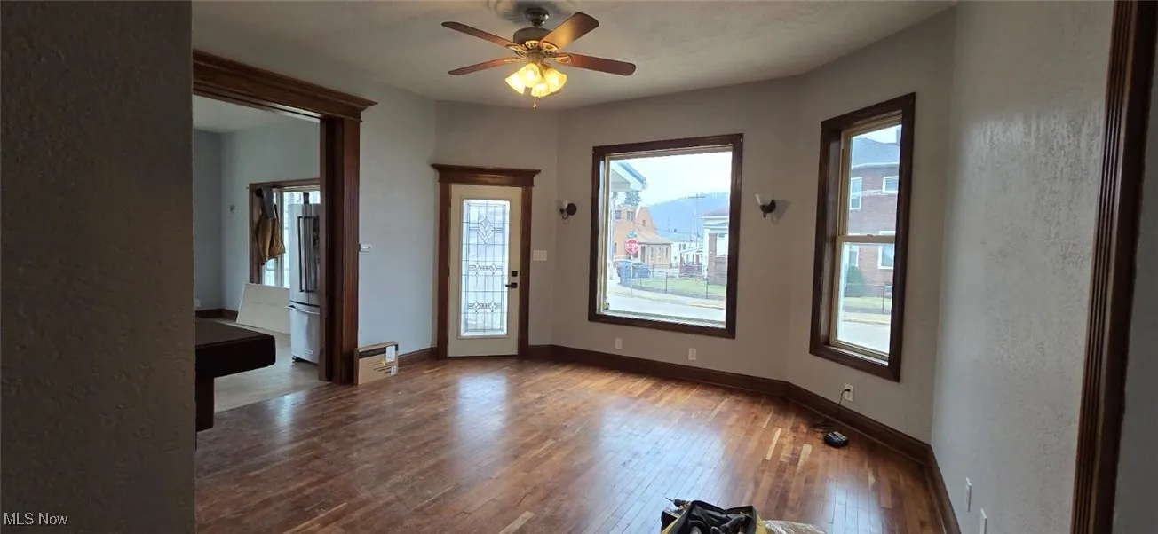 Empty room featuring hardwood / wood-style floors, ceiling fan, and a textured wall