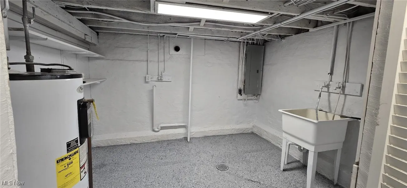 Unfinished basement featuring water heater and electric panel