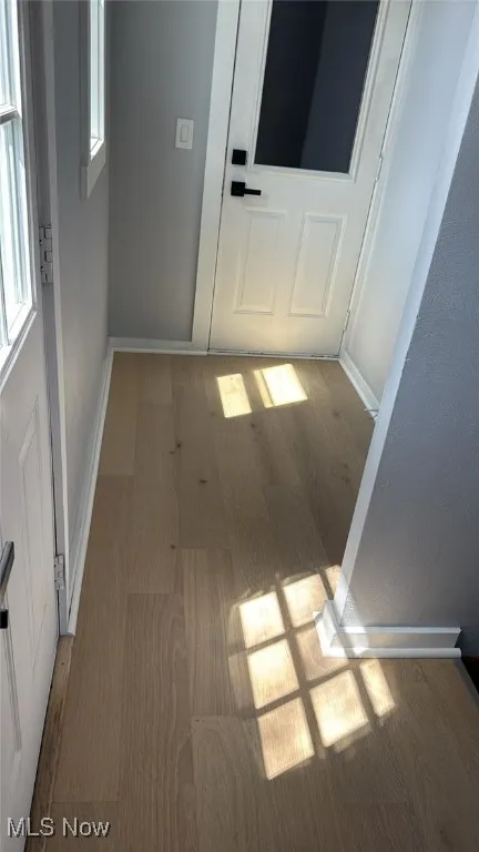 Corridor featuring healthy amount of natural light and wood finished floors