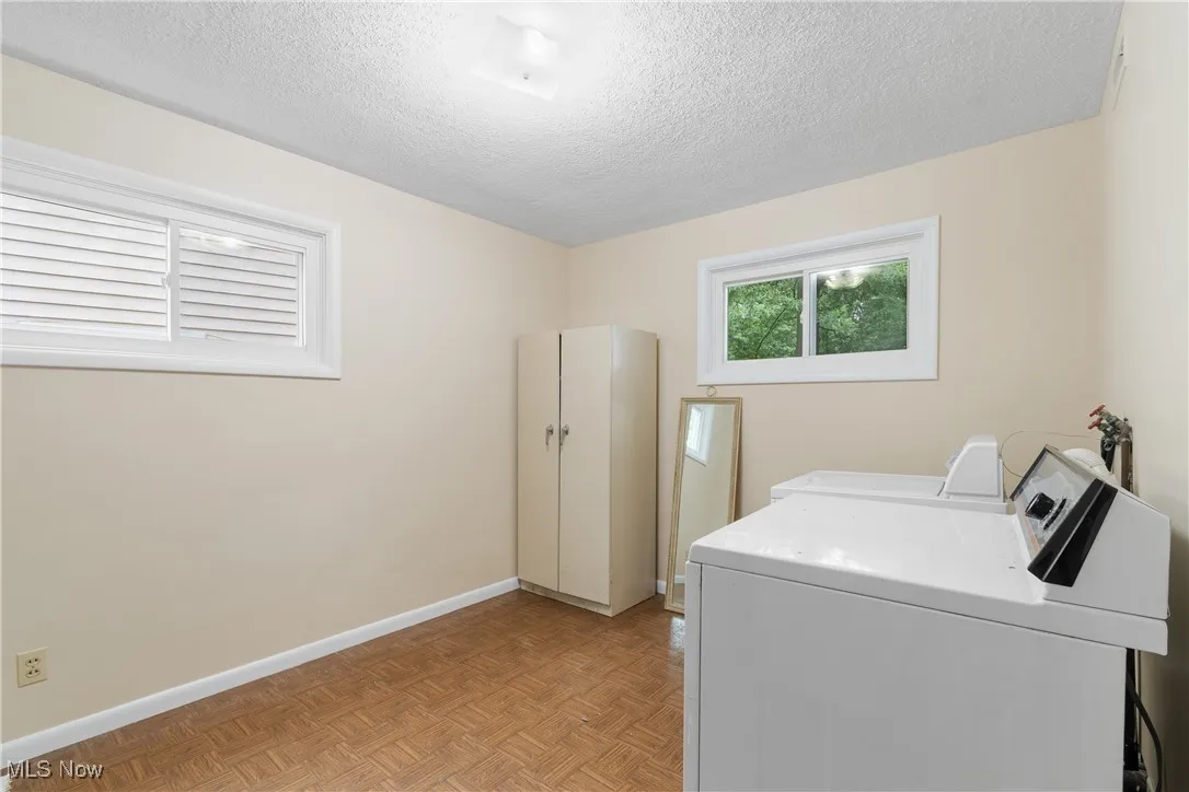 Washroom with washer and dryer and a textured ceiling