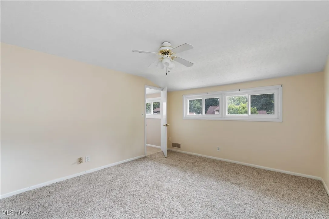 Carpeted spare room with a ceiling fan and lofted ceiling