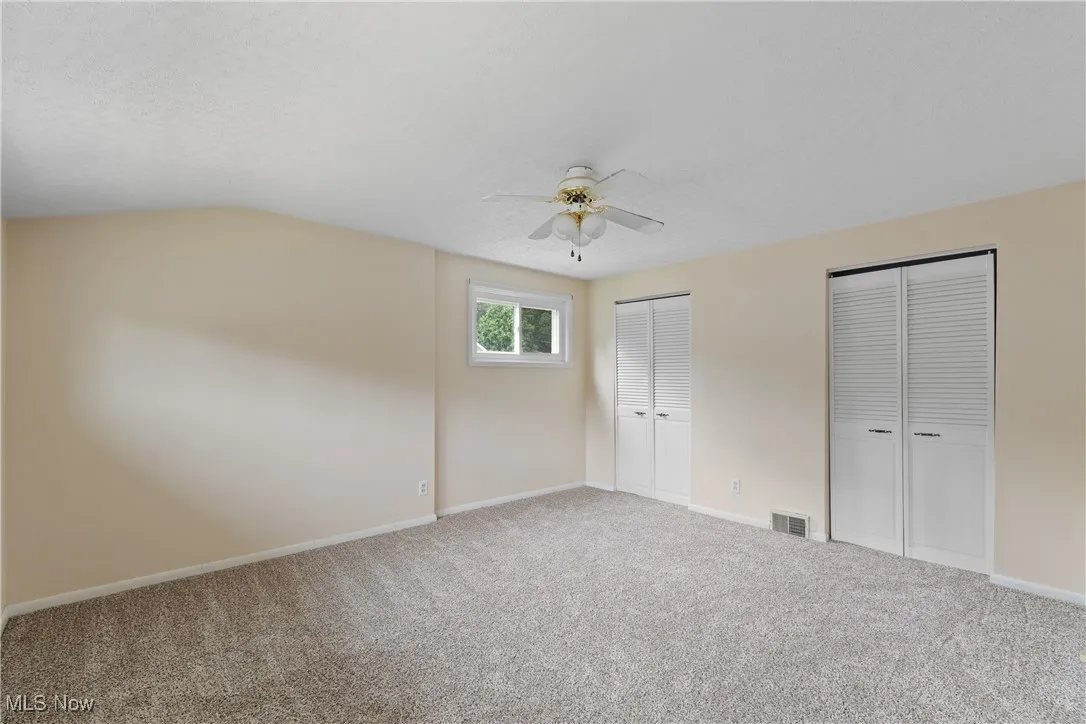 Unfurnished bedroom featuring two closets, carpet floors, ceiling fan, and a textured ceiling