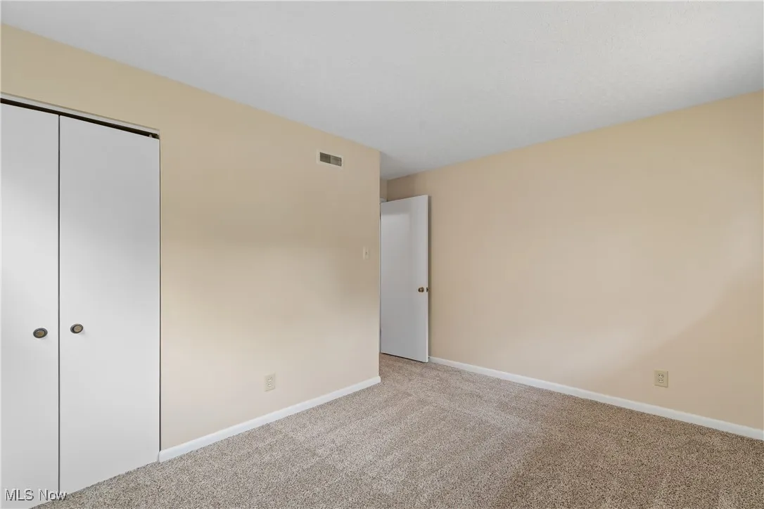 Unfurnished bedroom with light carpet and a closet