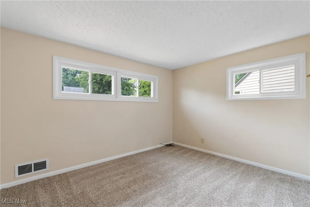 Carpeted spare room with baseboards and a textured ceiling