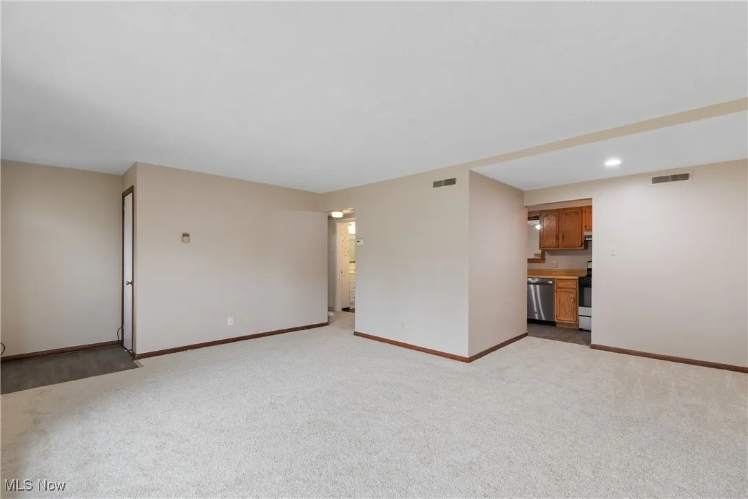 Unfurnished living room with light colored carpet and recessed lighting