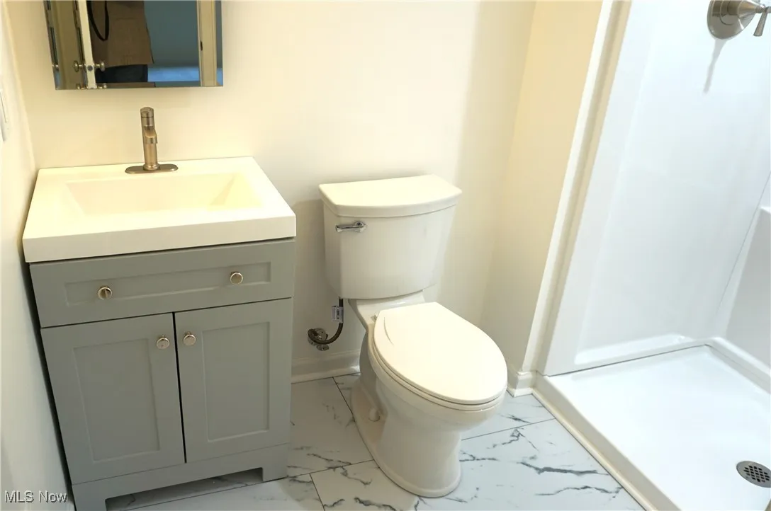 Bathroom featuring marble finish flooring, vanity, and a shower stall