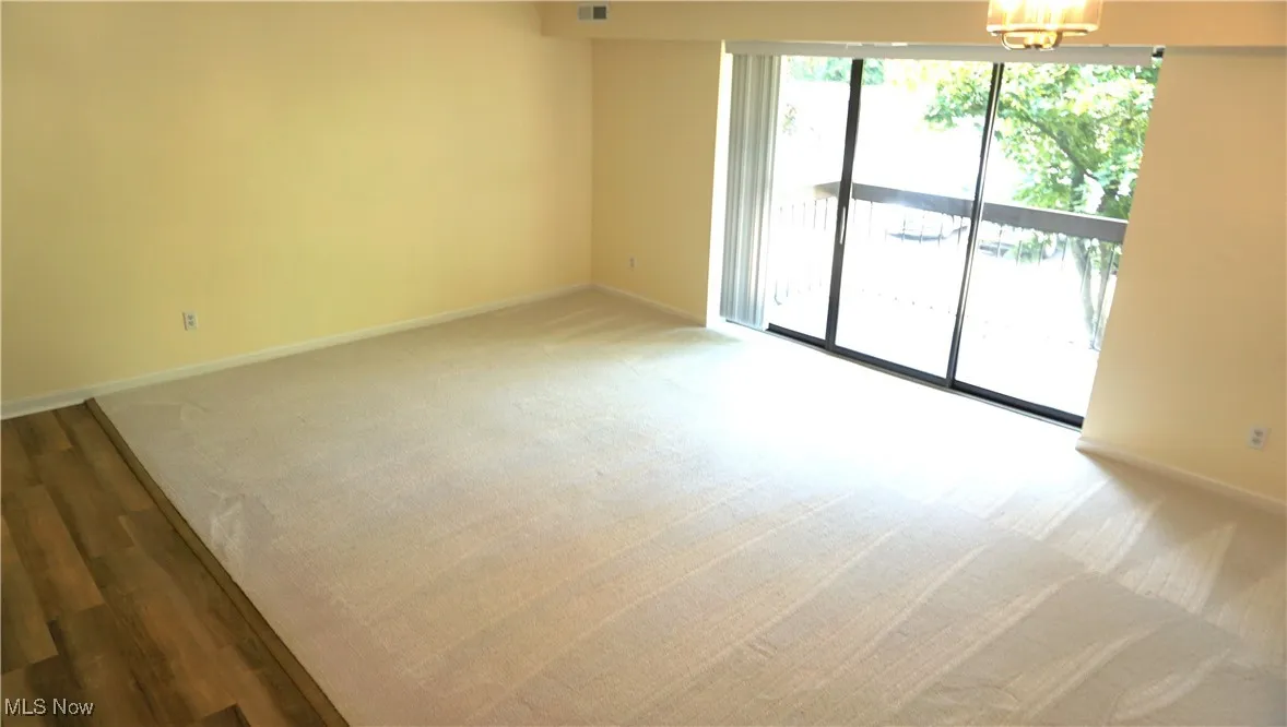Unfurnished room featuring a chandelier and light carpet