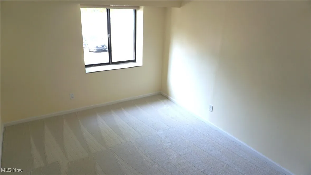 Spare room featuring light colored carpet and baseboards