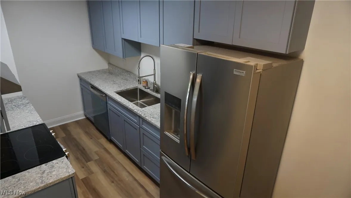 Kitchen featuring stainless steel appliances, dark wood-style floors, and light stone countertops