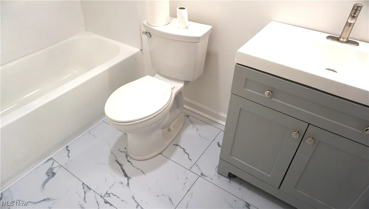 Bathroom with marble finish floors, vanity, and a bath