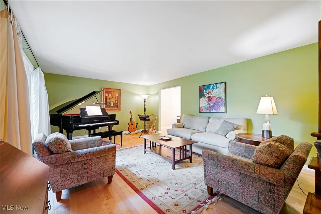 Front living room with wood flooring and baby grand piano which is included in the sale.