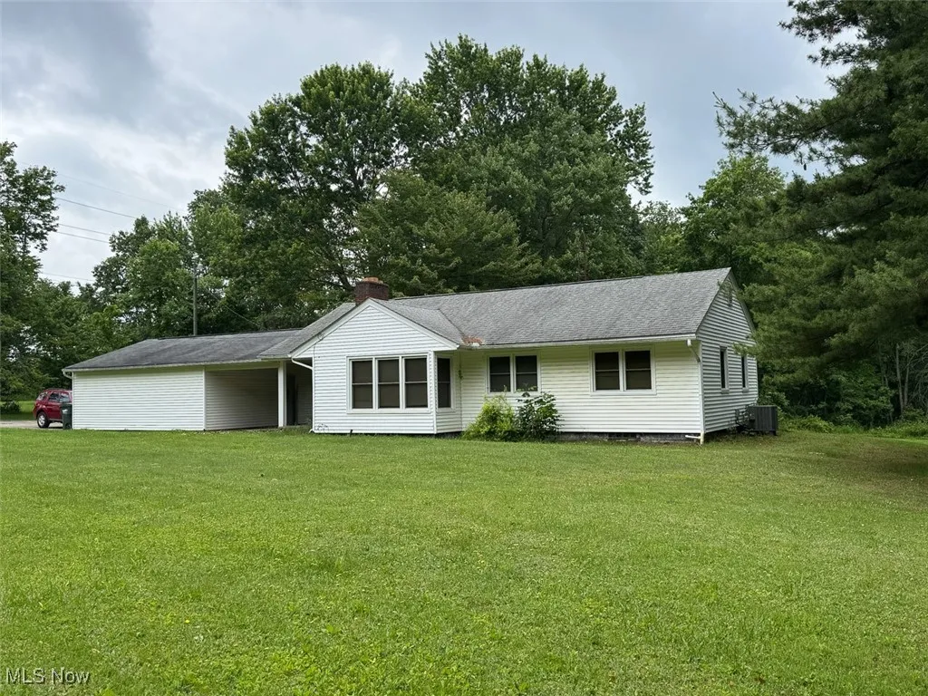Ranch-style home featuring a front lawn, an attached carport, and a chimney