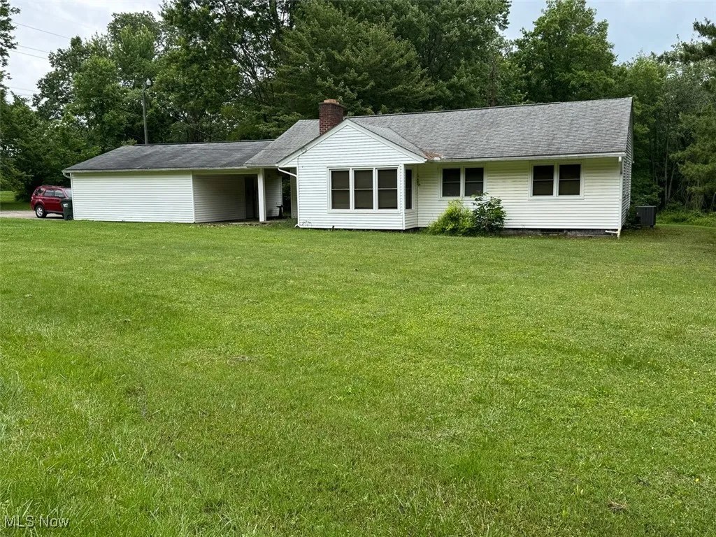 Ranch-style home featuring a front lawn and a chimney