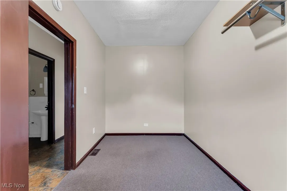 Empty room with a textured ceiling and carpet floors
