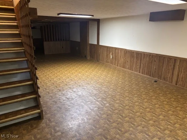 Finished basement with wainscoting, stairway, and wood walls