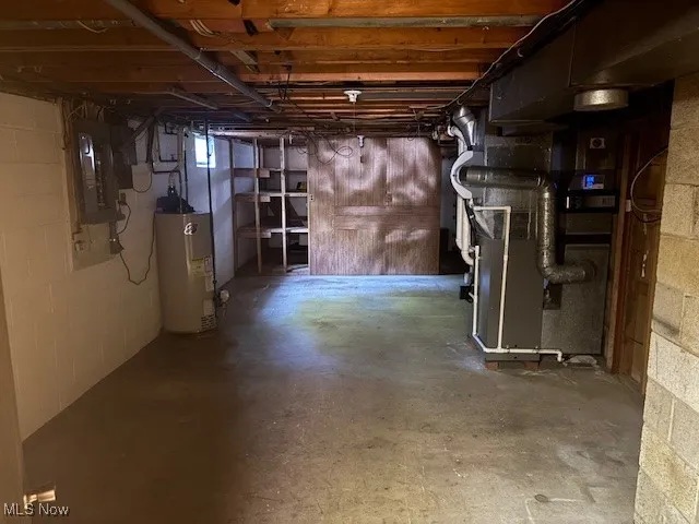 Basement featuring heating unit, water heater, and electric panel