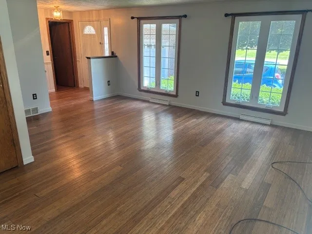 Unfurnished living room with plenty of natural light and dark wood finished floors