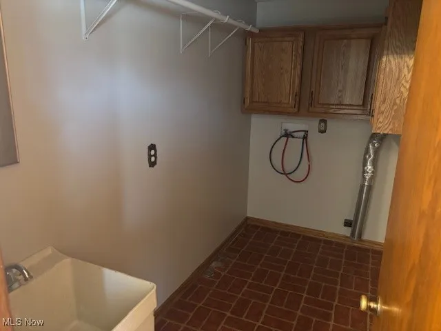 Washroom featuring washer hookup, brick patterned floors, and cabinet space