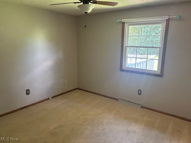 Spare room featuring a ceiling fan and light colored carpet