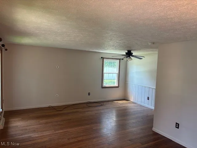 Spare room featuring a textured ceiling, dark wood finished floors, and ceiling fan