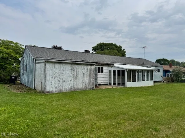 Back of property featuring a sunroom and a yard