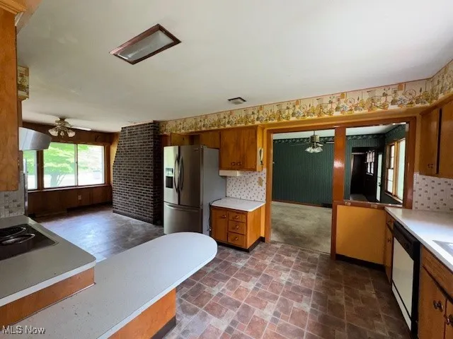 Kitchen featuring a ceiling fan, brown cabinets, light countertops, stainless steel fridge, and decorative backsplash