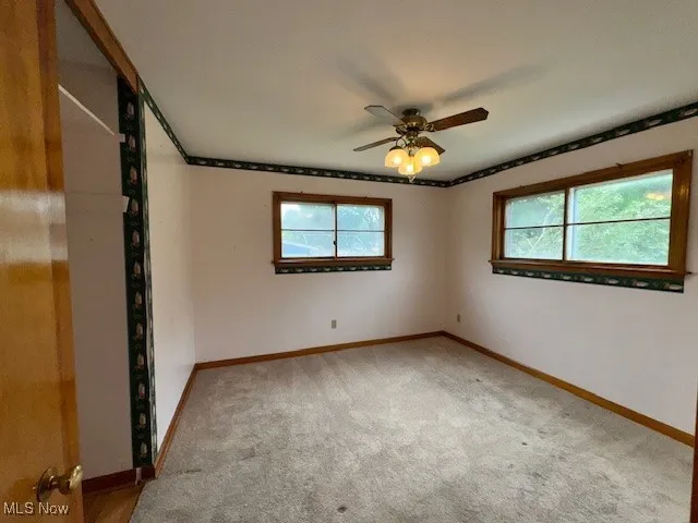 Unfurnished room featuring plenty of natural light, carpet floors, ceiling fan, and ornamental molding