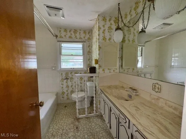 Full bath featuring vanity and wallpapered walls