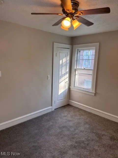 Carpeted spare room with a textured ceiling and ceiling fan