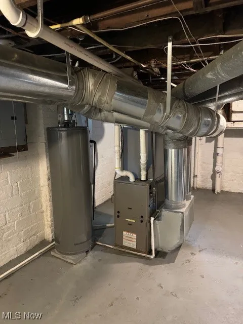 Utility room with water heater, electric panel, and heating unit