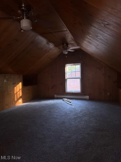 Additional living space featuring ceiling fan, wooden walls, carpet floors, vaulted ceiling, and wooden ceiling