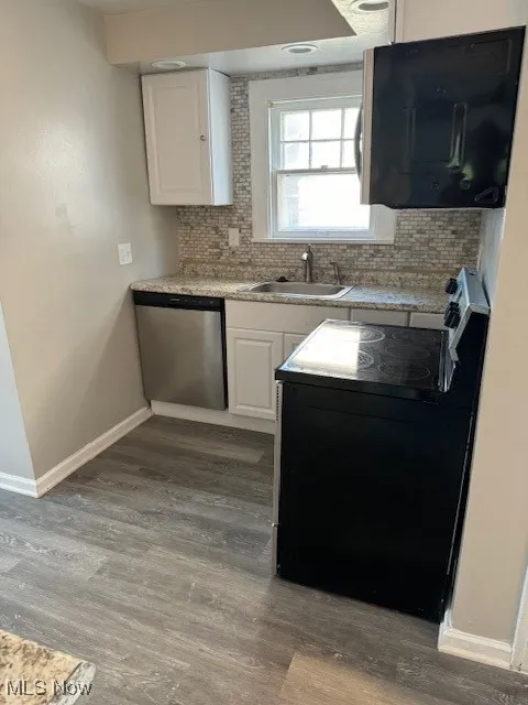 Kitchen featuring range, white cabinetry, dishwashing machine, and tasteful backsplash
