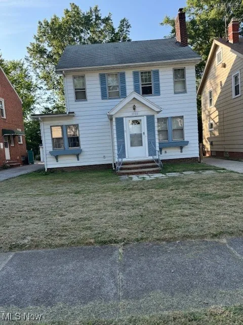 Colonial-style house with a chimney, entry steps, and a front lawn