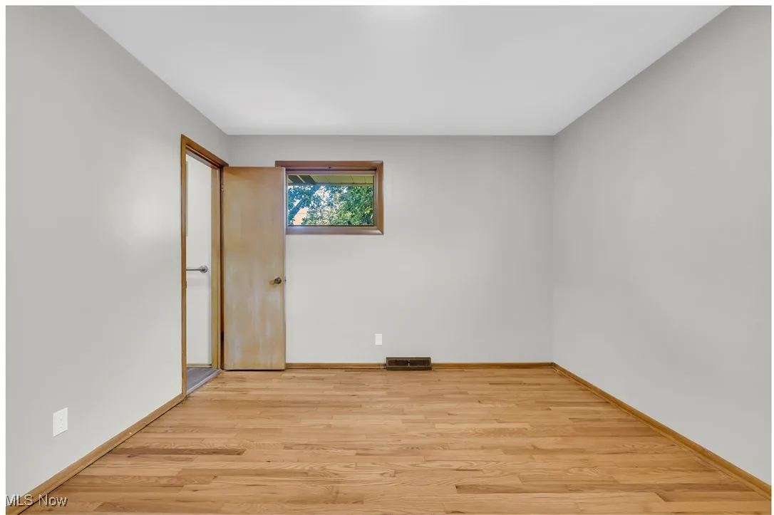 Unfurnished room featuring light wood finished floors and baseboards