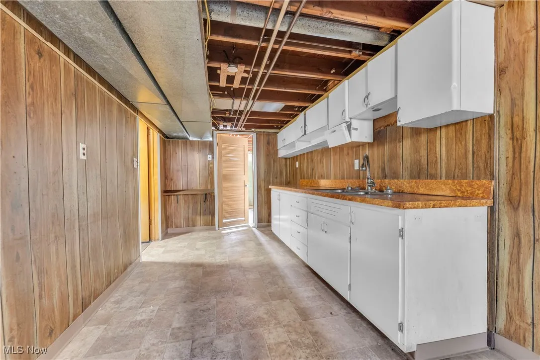 Kitchen featuring wooden walls and white cabinetry