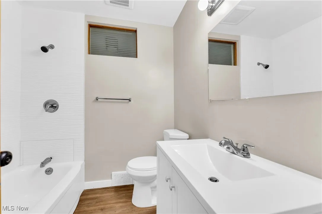 Bathroom with vanity, wood finished floors, and shower / bath combination
