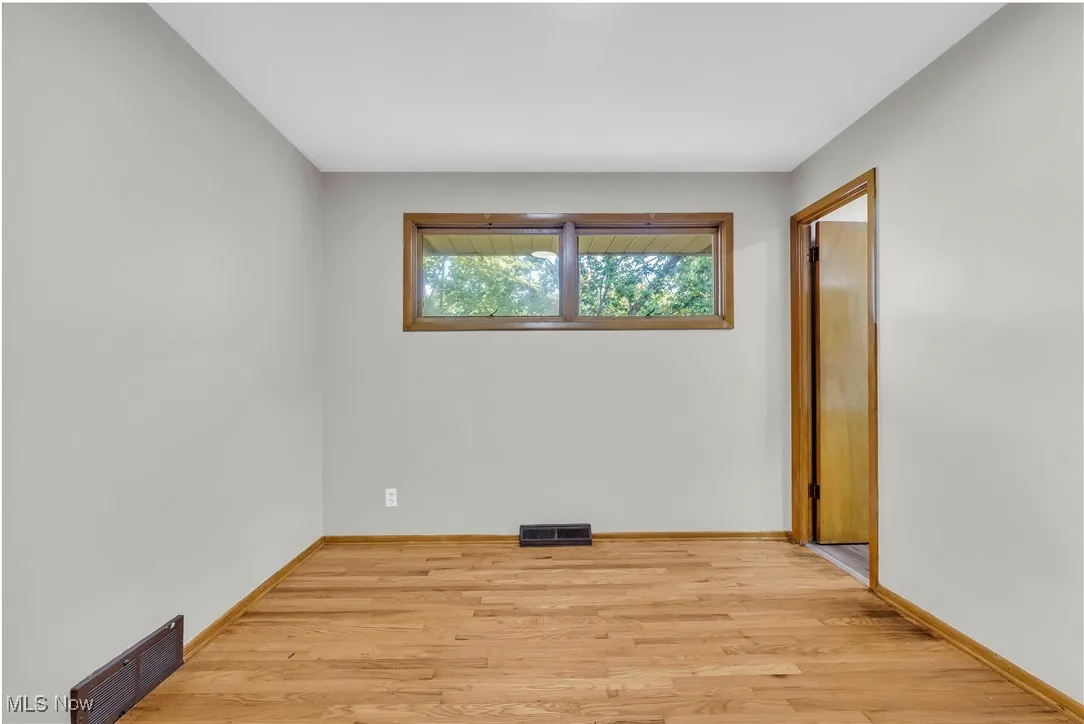 Unfurnished room with light wood finished floors and baseboards