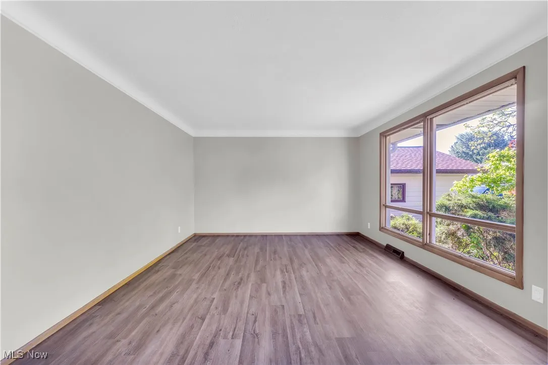 Unfurnished room with wood finished floors and ornamental molding