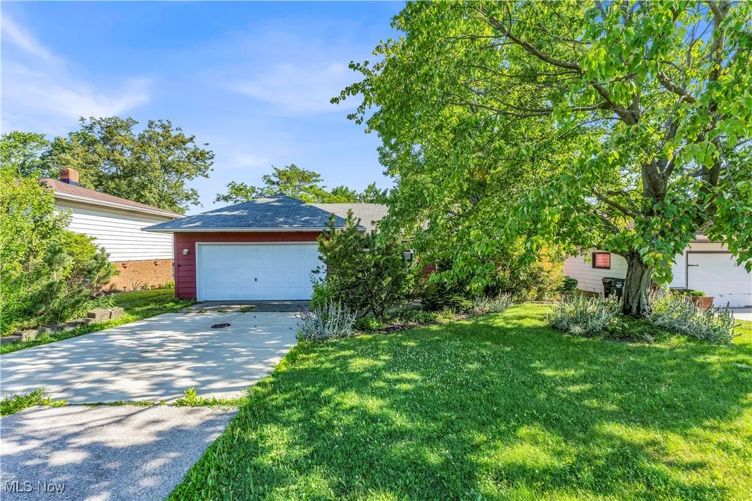 View of front facade with driveway, a front yard, and an attached garage
