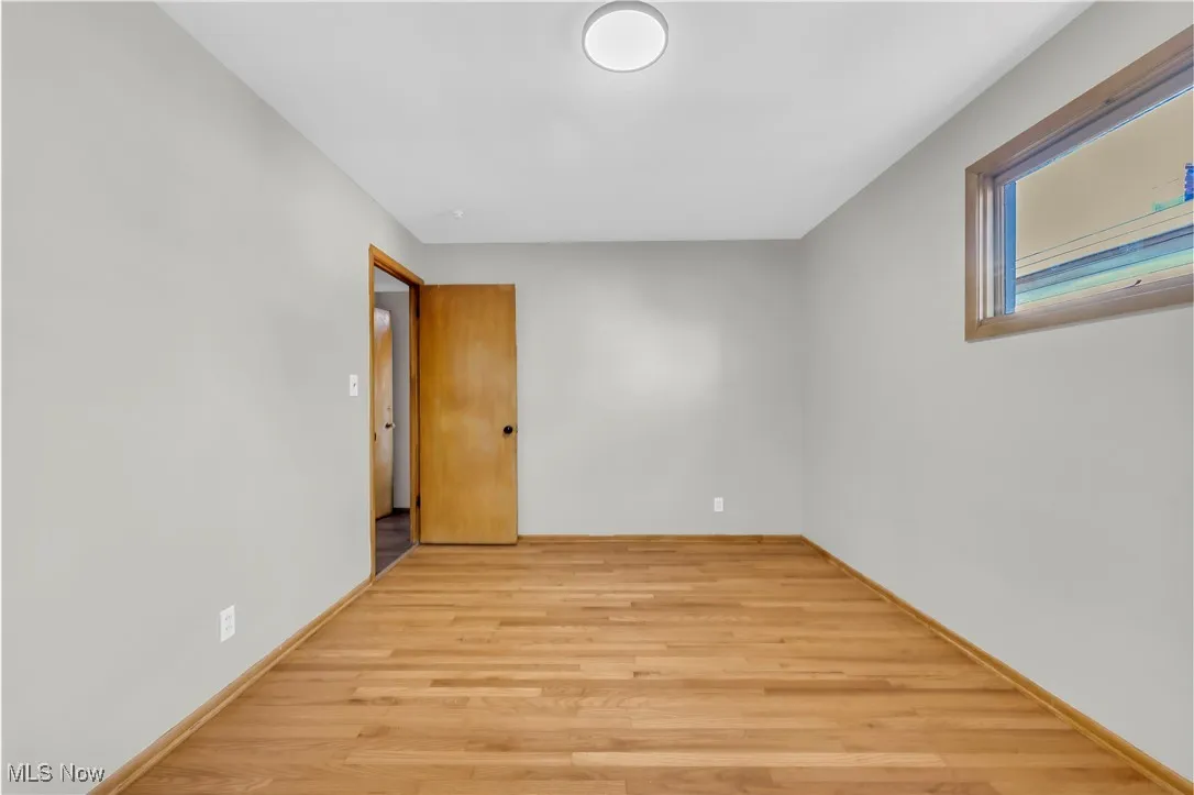 Unfurnished room featuring light wood finished floors and baseboards