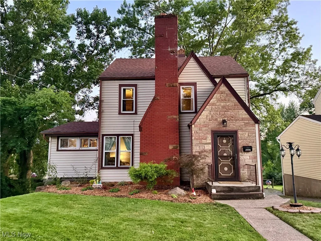 Tudor house with a front yard, a shingled roof, and a chimney
