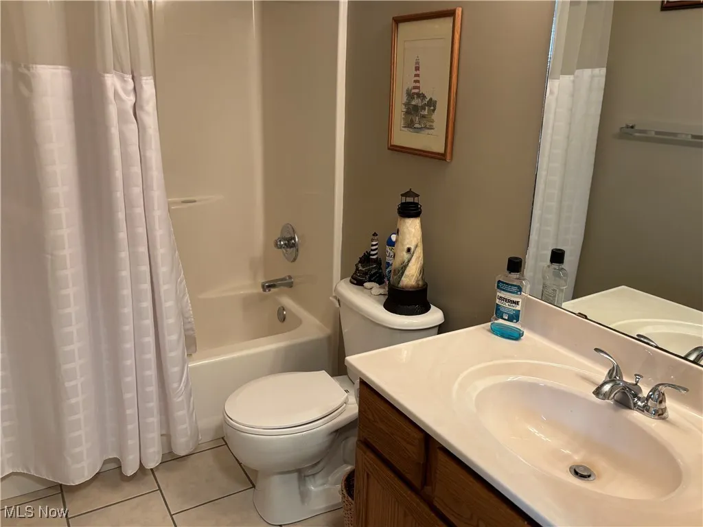 Full bathroom with tile patterned flooring, vanity, and shower / bath combination with curtain