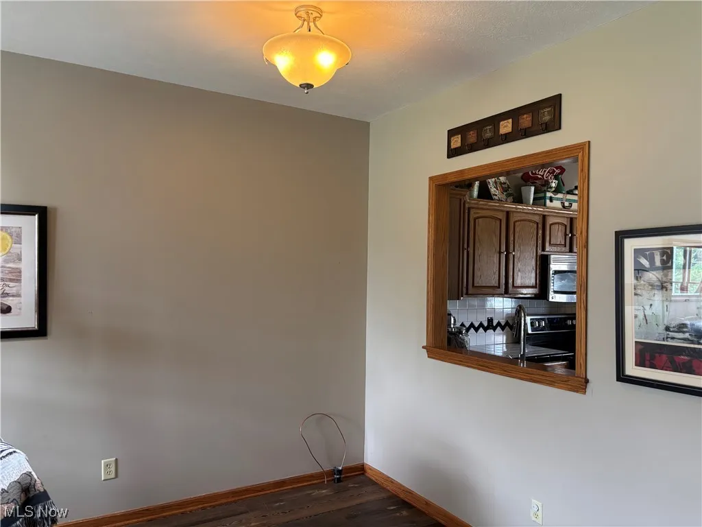 Dining space with dark wood-style flooring and baseboards