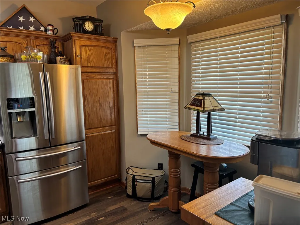Kitchen with stainless steel fridge, dark wood finished floors, and brown cabinets