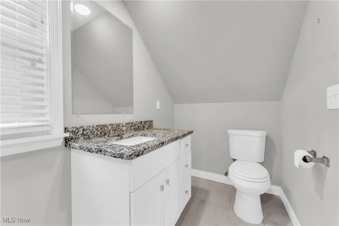 Bathroom with vaulted ceiling, vanity, and tile patterned floors